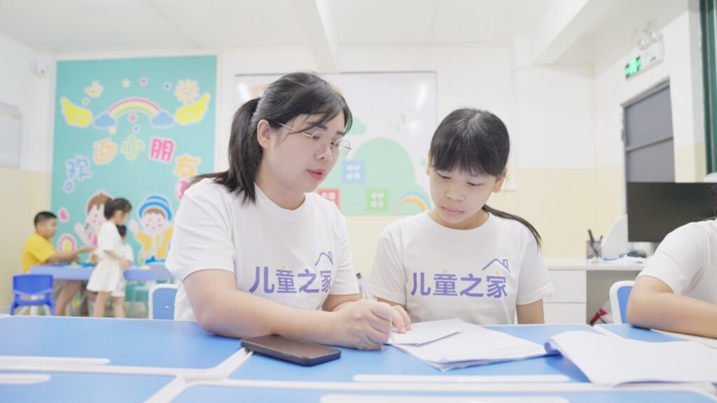 A childcare center teacher at a supplier partner's facility helping a worker's child with homework